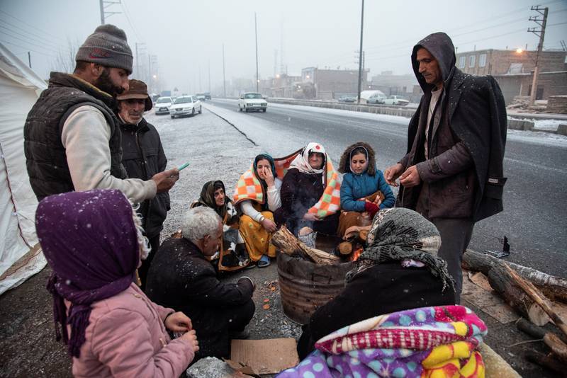 Residents in an outlying area gather by a roadside as snow falls. Reuters
