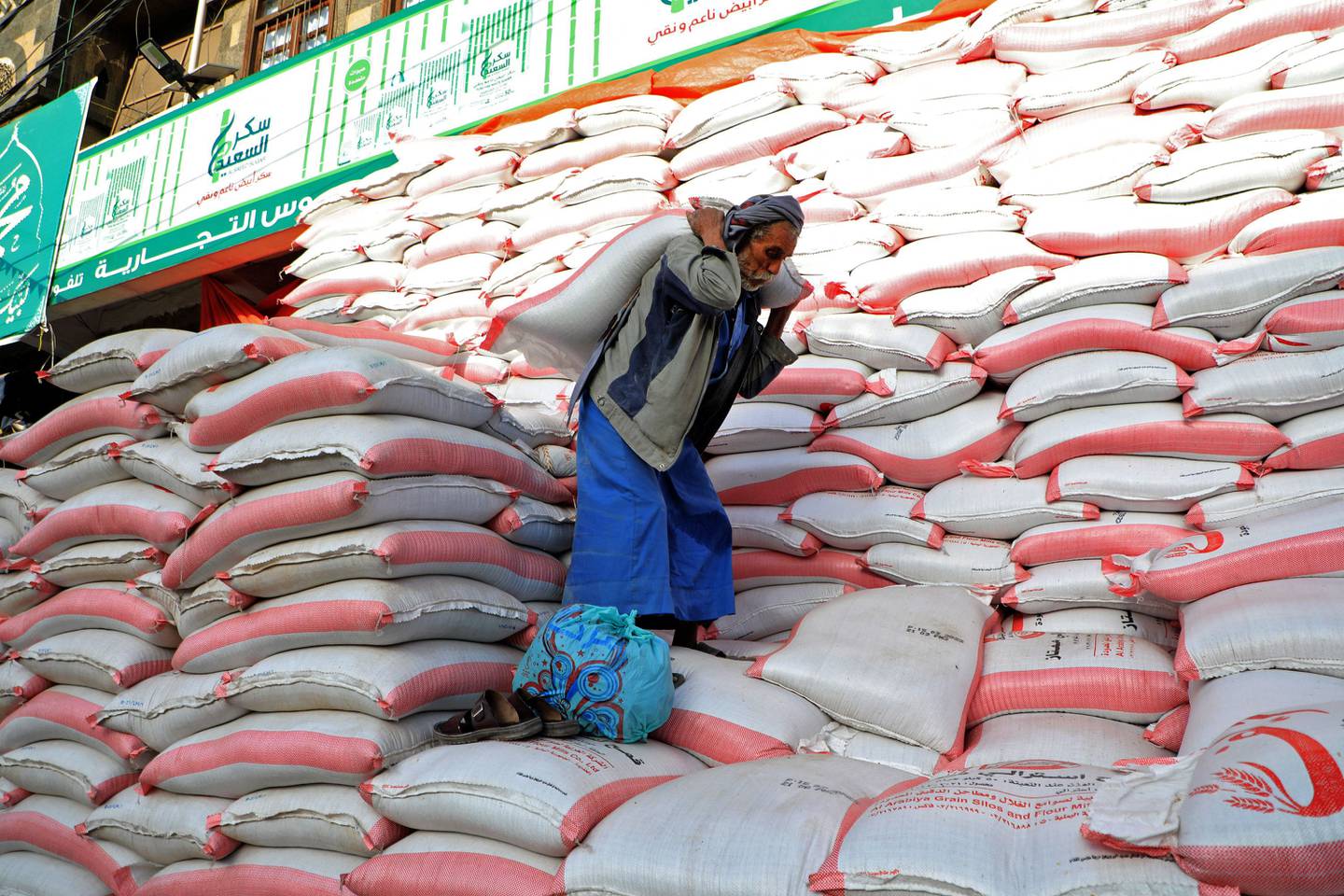 A Yemeni carries a bag of flour outside a wholesale store in the capital, Sanaa. AFP