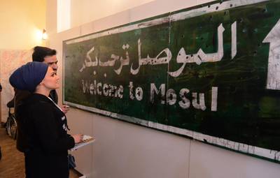 Iraqis stand in front of a 'Welcome to Mosul' road sign displayed at an art hall in the museum of the northern Iraqi city of Mosul on January 29. AFP