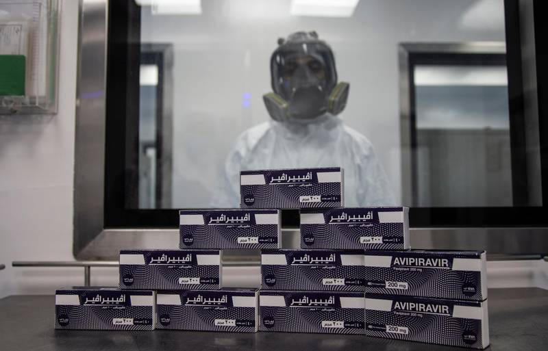 epa08508741 An employee wearing a full-face mask poses behind stacked boxes of the antiviral medication favipiravir at the laboratories of the Eva Pharma company in Cairo, Egypt, 25 June 2020. Favipiravir appears to have been proven effective in treating COVID-19 patients in Russia, while ongoing trials of the drug are taking place in Japan and other countries. In addition, the Egyptian drugmaker has reached a landmark deal with US company Gilead Sciences Inc. licensing the former to manufacture Gilead's antiviral drug remdesivir – another experimental treatment for patients suffering from the pandemic COVID-19 disease caused by the SARS-CoV-2 coronavirus – and distribute it in 127 countries.  EPA/MOHAMED HOSSAM