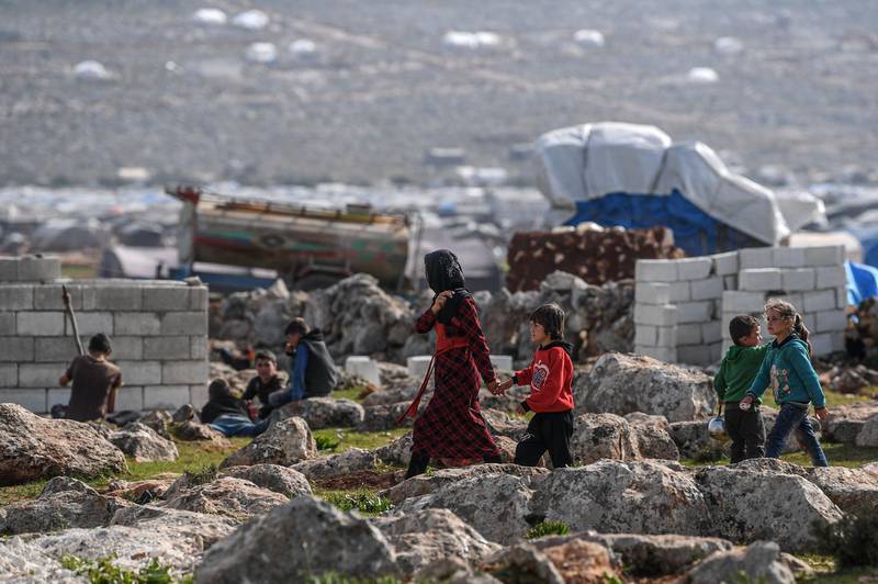 Resident of the camp at Kafr Lusin walk among concrete homes being built by Turkish NGOs. AFP