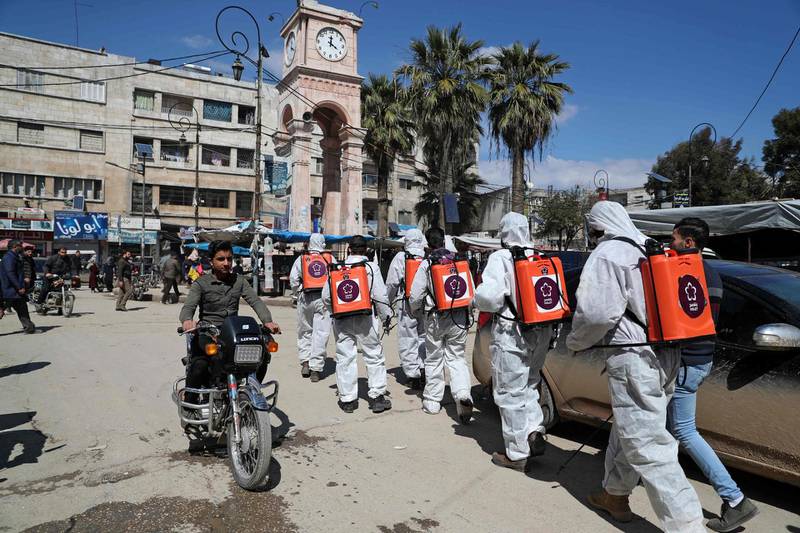 Members of the Syrian Violet NGO disinfect the streets of Syria's northwestern Idlib city. AFP