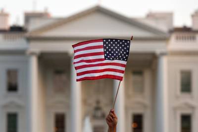 FILE - In this Sept. 5, 2017, file photo, a flag is waved outside the White House, in Washington. The Trump administration is extending a ban on green cards issued outside the United States until the end of 202 and adding many temporary work visas to the freeze, including those used heavily by technology companies and multinational corporations. (AP Photo/Carolyn Kaster, File)