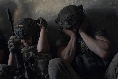 Ukrainian soldiers cover their ears to protect from Russian tank shelling in a shelter on the front line in the Zaporizhzhia region in July