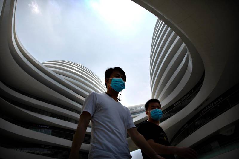People walk across a plaza at a shopping and office complex in Beijing, China. AP Photo