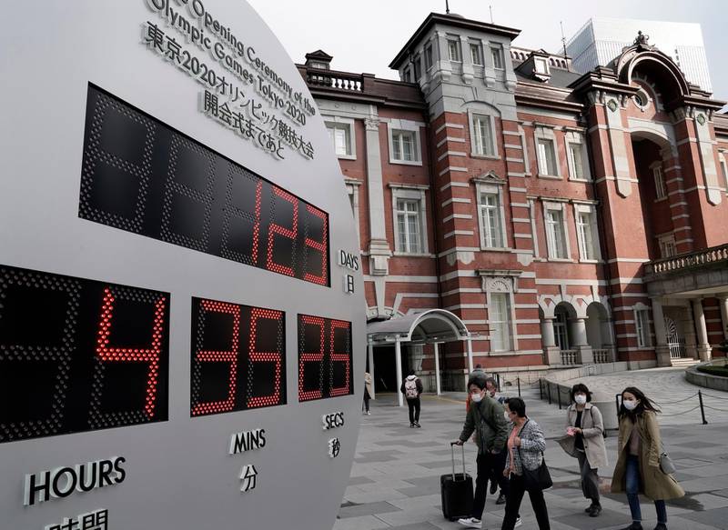 Pedestrians wearing masks walk past a countdown clock displaying the time until the opening of the Tokyo Olympic Games outside Tokyo railway station. Japanese Prime Minister Shinzo Abe said postponement of Games is a genuine possibility. EPA