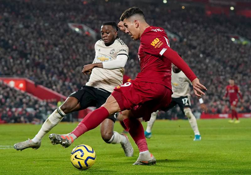 Manchester United's Aaron Wan-Bissaka, left, attempts to block a cross from Roberto Firmino AP Photo