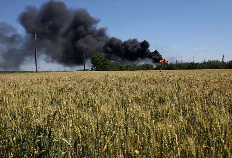 A fire from a gas processing plant continues to burn behind a field of wheat after it was hit by shelling a few days earlier in Andriivka, in the Kharkiv region. Reuters