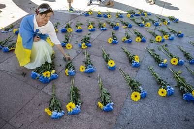 A woman lays flowers during a demonstration against the  invasion of Ukraine in front of the Palais des Nations, in Geneva, Switzerland. EPA