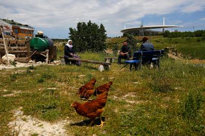 Local residents sit at an area, near to Ataturk Olympic Stadium, background, in Istanbul. AP Photo