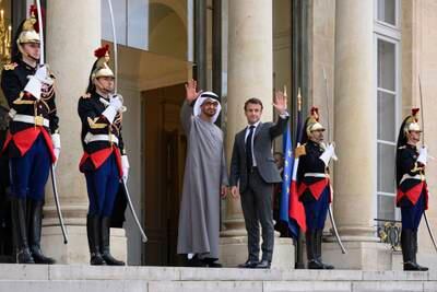Sheikh Mohamed and Mr Macron wave to the media before their meeting