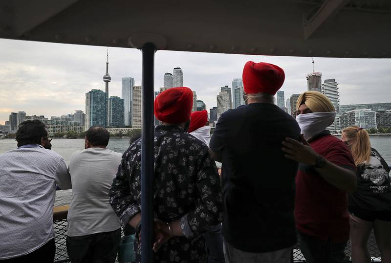 People look at the city skyline on a ferry coming back from Centre Island to Toronto, Canada. AP