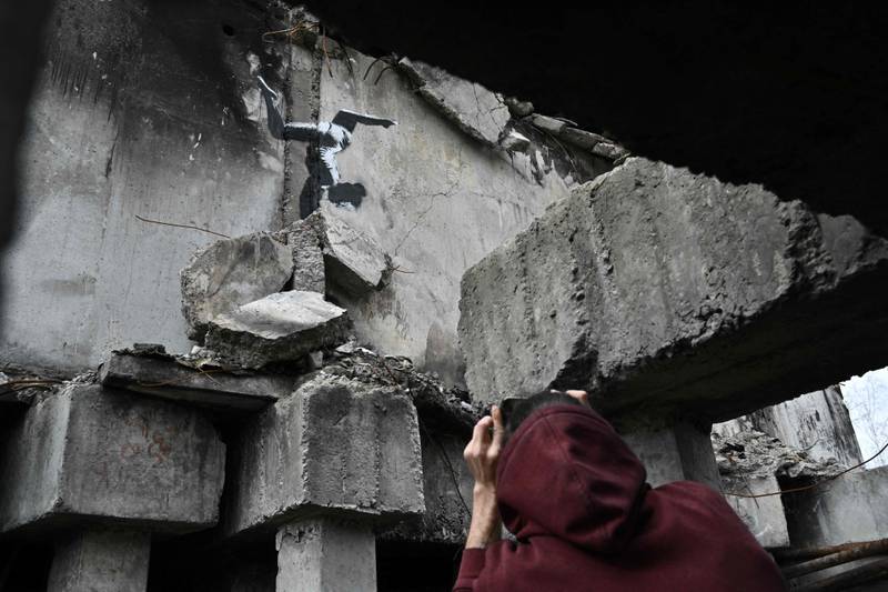 A resident takes a picture of Banksy gymnast in Borodyanka. AFP