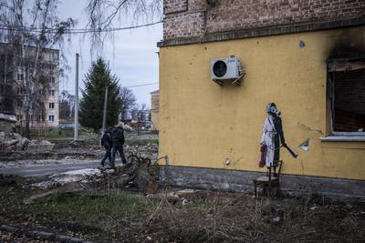 A figure in a dressing gown holds a fire extinguisher and wears a gas mask in Hostomel near Antonov International Airport in Kyiv Region. Getty 