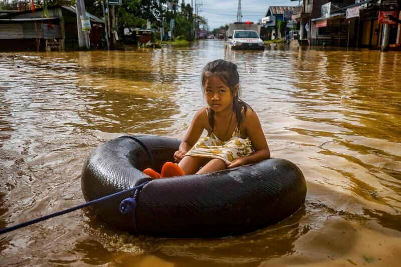 A child is pulled through floodwaters on an inflatable. Getty
