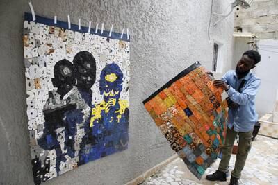 Ivorian artist Aristide Kouame, who creates art made out of plastic waste, works on a piece made of used flip-flops he collected from a beach in Abidjan. EPA