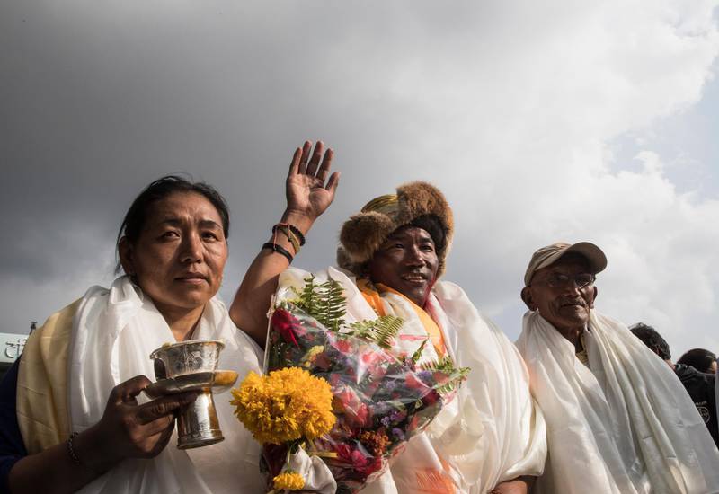 Kami Rita Sherpa waves as he stands between his wife and father. Narendra Shrestha / EPA