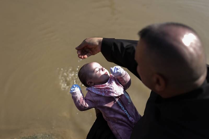 A baby is baptised in the river. EPA