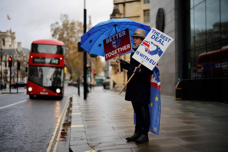 Anti-Brexiteer activist Steve Bray holds placards and an EU-themed umbrella as he stands outside a conference centre in central London on December 4, 2020, as talks continue on a trade deal between the EU and the UK. With just a month until Britain's post-Brexit future begins and trade talks with the European Union still deadlocked, the UK government on Tuesday urged firms to prepare as it scrambles to finish essential infrastructure. / AFP / Tolga Akmen
