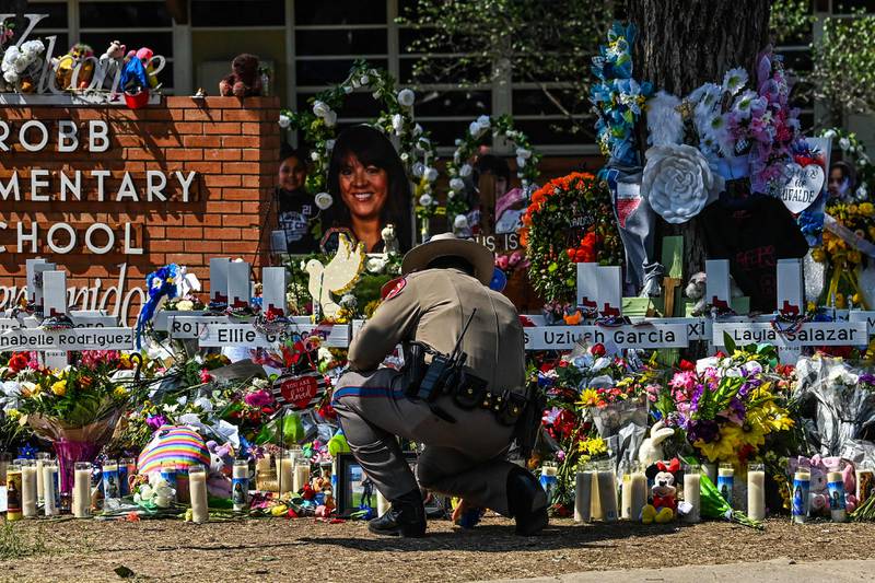 A police officer clears the memorial before the visit of US President Joe Biden at Robb Elementary School in Uvalde, Texas. AFP