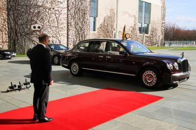 Mr Scholz waits as the car carrying King Charles arrives. Reuters