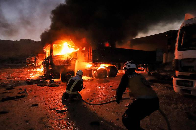 Members of the Syrian civil defence try to put out several trucks and freight vehicles on fire in the aftermath of air strikes at a depot near the Bab al-Hawa border crossing between Syria and Turkey in Syria's rebel-held northwestern Idlib province. AFP