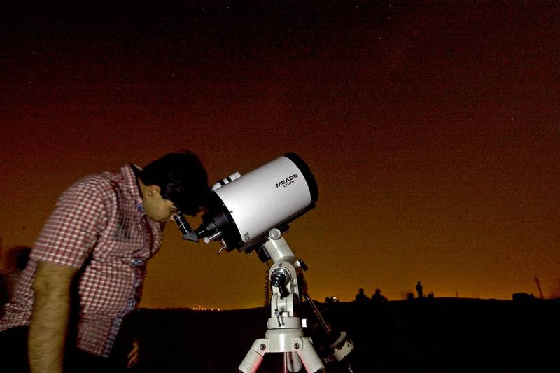 Lehbab - August 13, 2009 - Amol Mane, a member of the Dubai Astronomy Club looks through a Meade 8 inch telescope during a gathering sponsored by the group for stargazers to view the Perseids meteor shower near Lehbab (midway between Dubai and Hatta), August 13, 2009. About 200 people gathered to watch the Perseids meteor shower. (Photo by Jeff Topping/The National)  *** Local Caption ***  JT004-0813-PERSEIDS_MG_8147.jpg
