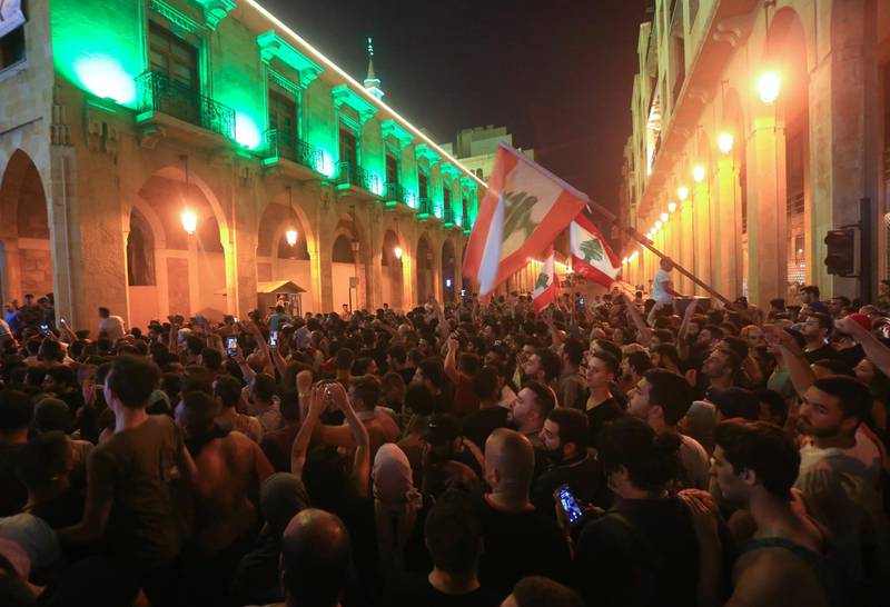 Demonstrators wave flags during a protest against a government decision to tax calls made on messaging applications on October 17, 2019 outside the government palace in Beirut. - Hundreds took to the streets across Lebanon on October 17 to protest dire economic conditions after a government decision to tax calls made on messaging applications sparked widespread outrage. (Photo by STRINGER / AFP)