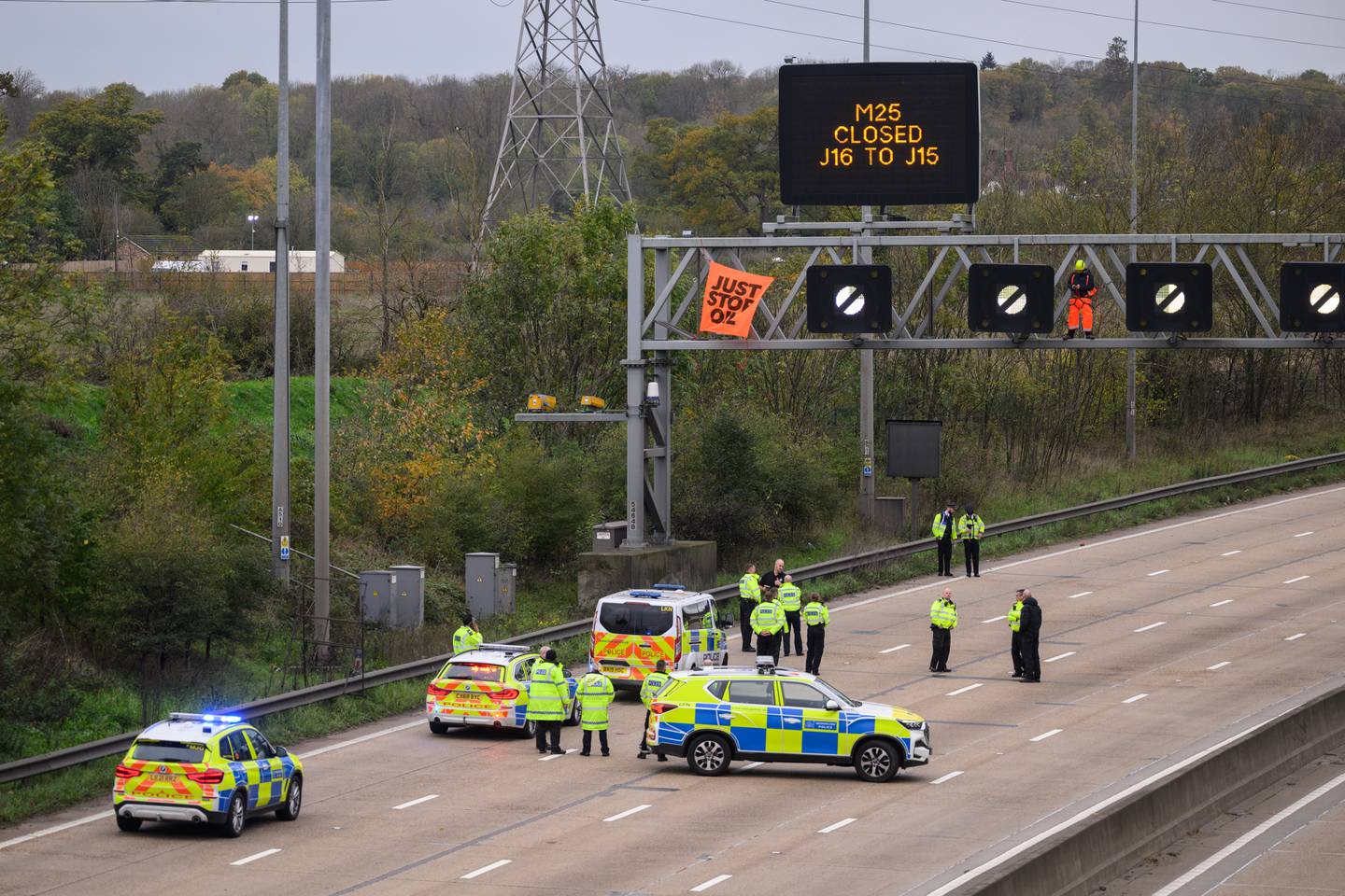 Police officers talk to a Just Stop Oil activist on an electronic traffic sign along the M25 in London on November 10. Getty