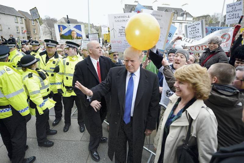 EDINBURGH, SCOTLAND - APRIL 25:  Donald Trump is hit on the head by a member of public holding a balloon following addressing the Scottish Parliament on April 25, 20012. Trump spoke of his concerns over a proposed wind farm, mooted to built near his new GBP 1 billion golf resort, telling the Scottish Parliament that they will destroy tourism in the country.  (Photo by Jeff J Mitchell/Getty Images)