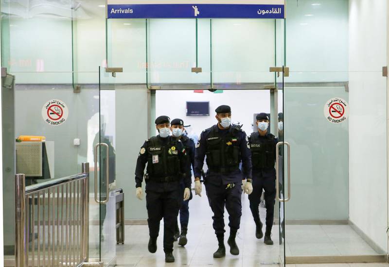 TOPSHOT - Kuwaiti policemen wearing protective masks wait at Sheikh Saad Airport in Kuwait City, on February 22, 2020, before transferring Kuwaitis arriving from Iran to a hospital to be tested for coronavirus. Iran ordered the closure of schools, universities and cultural centres after a coronavirus outbreak that has killed five people in the Islamic republic, the most outside the Far East. / AFP / YASSER AL-ZAYYAT
