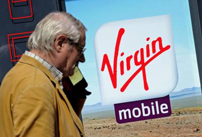 A man gives a phone call as he walks by the logo of mobile phone operator Virgin Mobile on May 17, 2014 in Lens. AFP PHOTO PHILIPPE HUGUEN / AFP PHOTO / PHILIPPE HUGUEN
