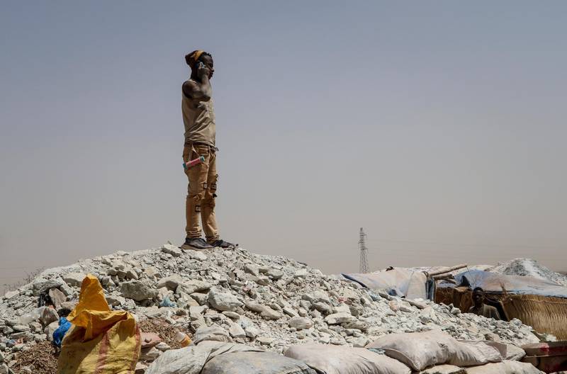 A miner stands on a mound of dirt to make a phone call, at a gold mine in Bouda, Burkina Faso. AP Photo