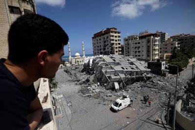 A man peers out to survey destroyed buildings in Gaza city, following Israeli air strikes. AFP