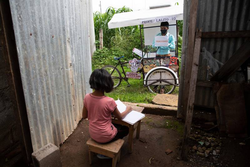 Gerardo Ixcoy teaches 12-year-old student Paola Ximena Conoz about fractions from his mobile classroom, parked just outside the door to her home in Santa Cruz del Quiche, Guatemala. AP Photo