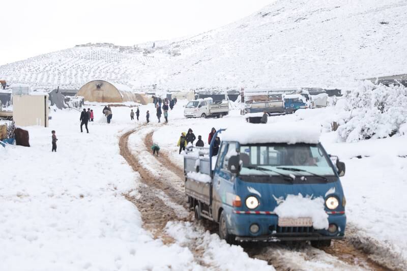Internally displaced Syrians stand in the snow