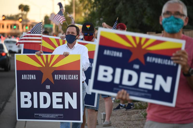 Members of the group "Arizona Republicans Who Believe In Treating Others With Respect" hold signs in support of Democratic presidential candidate Joe Biden, during evening rush hour in Phoenix, Arizona on October 16, 2020. Arizona has not elected a Democrat since Bill Clinton's second win in 1996, but is undergoing major demographic changes. The state best known abroad for the Grand Canyon is seeing a rapid growth in urban areas, among young college-educated voters, and in its robust Latino community -- groups that tend to favor the Democratic Party. But key to next month's election is that the average Arizona voter, whether Republican or Democrat, tends to be more moderate and is "tired of the President's behavior and the rhetoric coming from his campaign," according to Arizona State University politics lecturer Gina Woodall. / AFP / Robyn Beck
