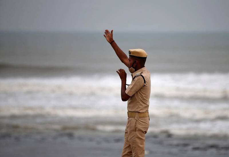 A police officer in Veraval, Gujarat, directs people to leave as waves approach the shore before the arrival of Cyclone Tauktae. Reuters