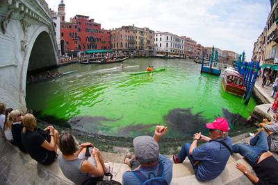 Fluorescent green waters below the Rialto Bridge as police continue to investigate the origin of the liquid.  AFP