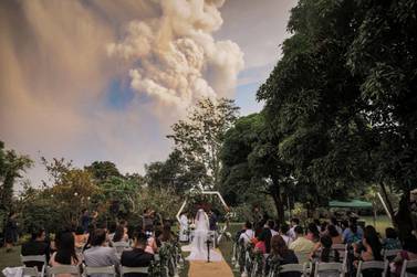 People attend a wedding ceremony as Taal Volcano sends out a column of ash in the background in Alfonso, Cavite, Philippines, Randolf Evan Photography via Reuters