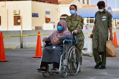 A US Air Force servicemember assists an Afghan woman at Naval Air Station Sigonella. Photo: US Department of Defence