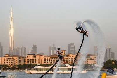 Athletes perform stunts with water jet packs on the first day of the Dubai watersport festival, organised by the Dubai International Marine Club (DIMC), near the Burj Khalifa skyscraper in the Gulf emirate on June 25, 2020.  / AFP / KARIM SAHIB
