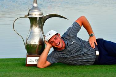 Bryson Dechambeau of United States poses with the winner's trophy while celebrating his victory in the the Dubai Desert Classic at Emirates Golf Club on January 27, 2019 in Dubai. / AFP / GIUSEPPE CACACE