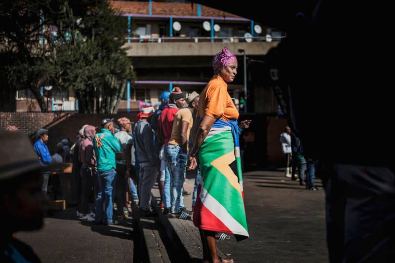 A woman wears a blanket printed with the South African national flag as she queues at the Kwa Mai Mai market in the Johannesburg CBD during a food distribution.  AFP