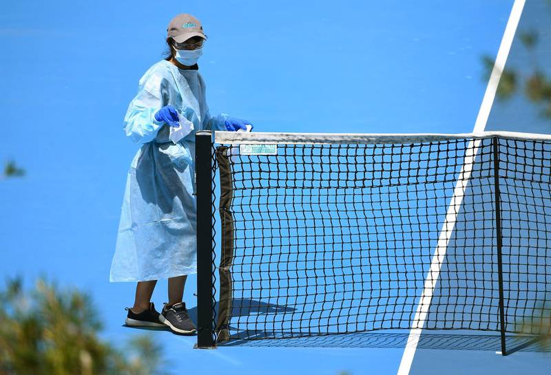 A cleaner wipes down the net after a player's practise session in Melbourne with players allowed to train while serving quarantine for two weeks ahead of the Australian Open tennis tournament. AFP