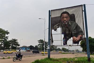 A man rides his motorcycle past a torned portrait of DR Congo's former president Joseph Kabila, on January 14, 2019, in the Nimite neighbourhood of the capital Kinshasa. Martin Fayulu, who came second in DR Congo's presidential election, has appealed to the Constitutional Court to annul the provisional result which awarded victory to his opposition rival Felix Tshisekedi, his lawyer said on January 12. Fayulu denounced the result as an "electoral coup" engineered by Kabila in which Tshisekedi was "totally complicit", saying the truth of what happened at the ballot box would only come out with a recount. / AFP / TONY KARUMBA
