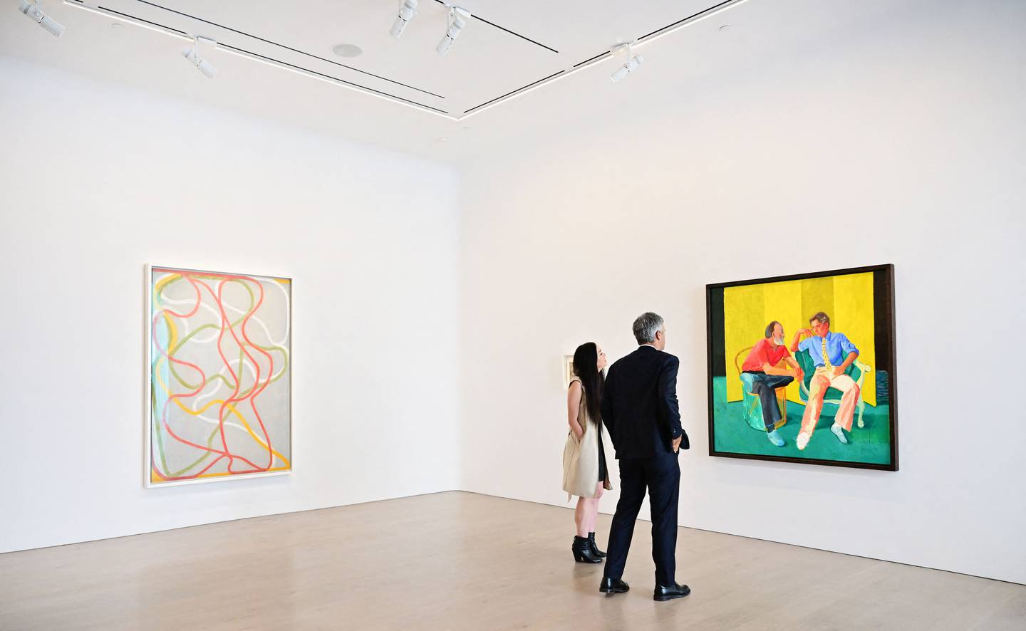 Alex Marshall, senior specialist and senior vice president at Christie's, views 'The Conversation' by David Hockney displayed beside 'The Attended' by Brice Marden during the media preview of Paul Allen's art Collection. AFP