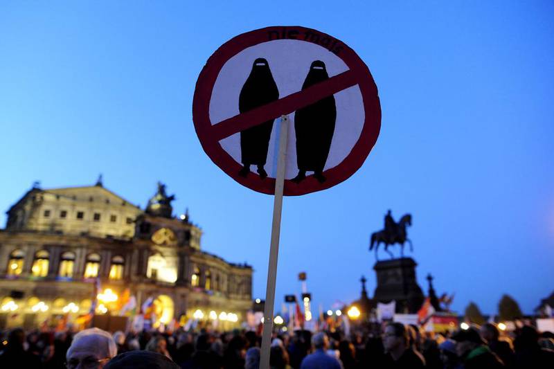 A supporter of the Pegida movement, holds a poster featuring a crossed sign on veiled women at a protest rally on October 12, 2015 on the theatre square in Dresden, eastern Germany. AFP