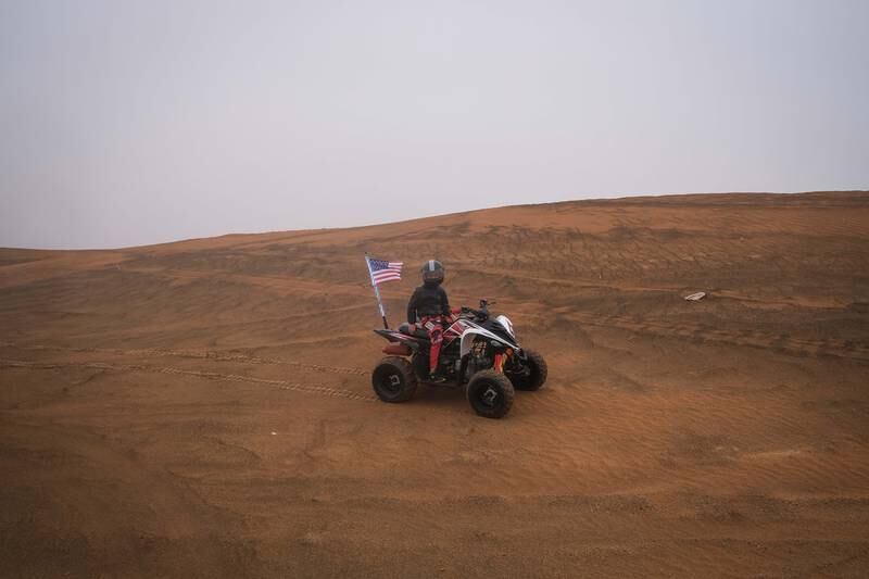 A young boy rides a quad bike in Sharjah's desert.