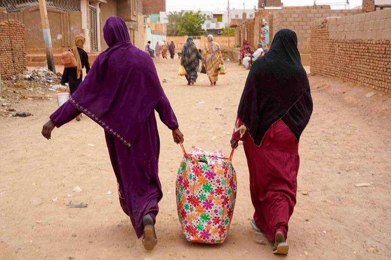 Women carry their belongings down a street in Omdurman, Khartoum's twin city, on Monday. AFP